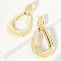Pair of gold-colored open teardrop dangle earrings on a white display